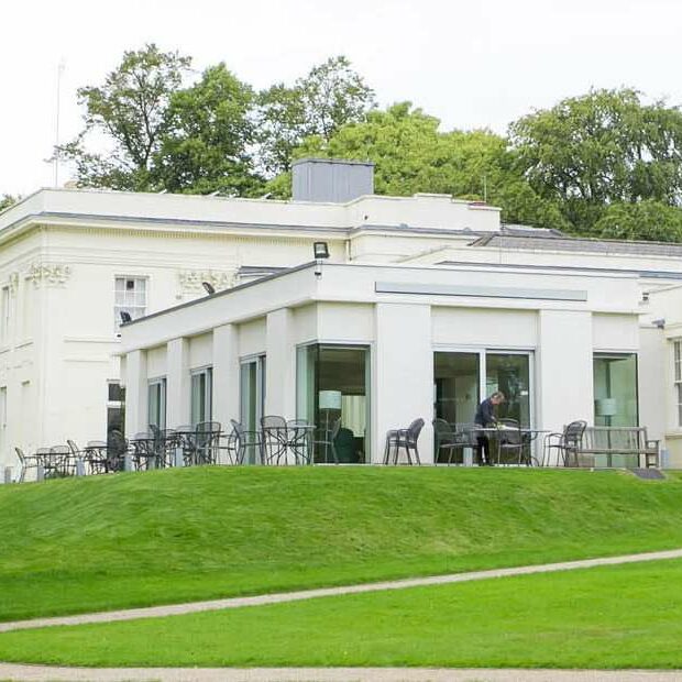 Photo of white building surrounded by grass and trees