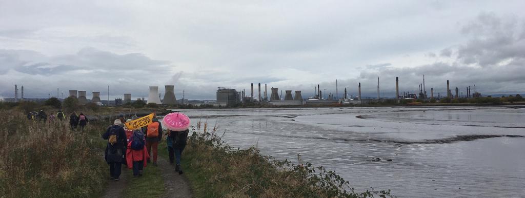 Photo of protesters walking along an estuary towards a huge power plant