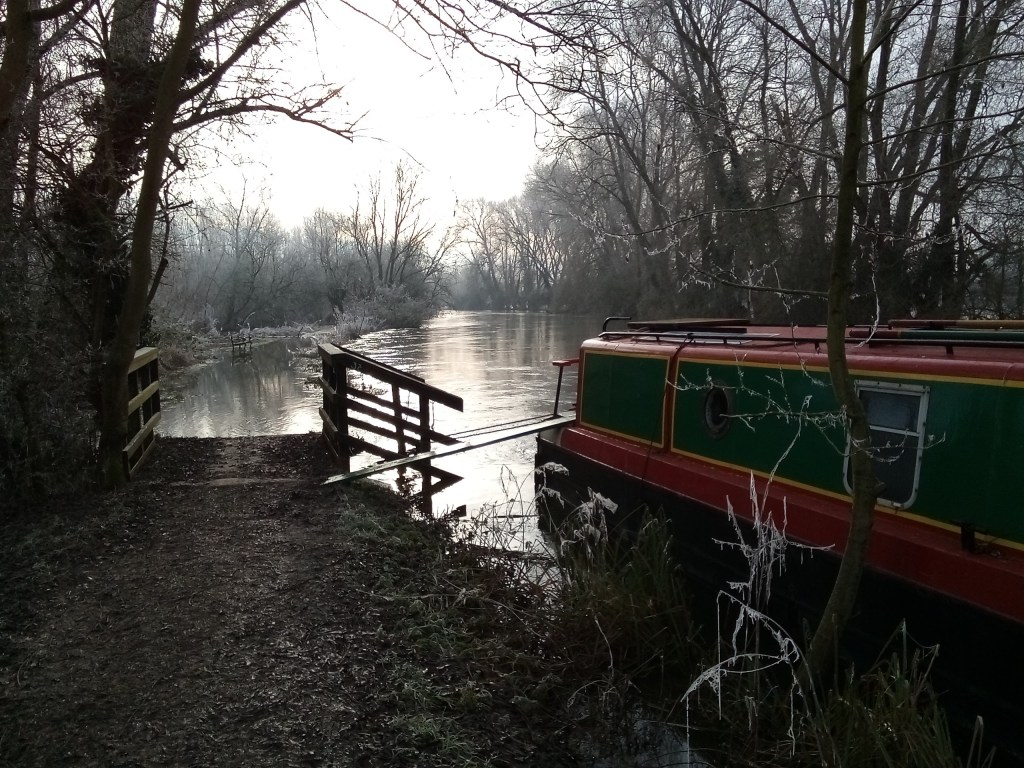 Winter scene of narrowboat on river Thames surrounded by trees